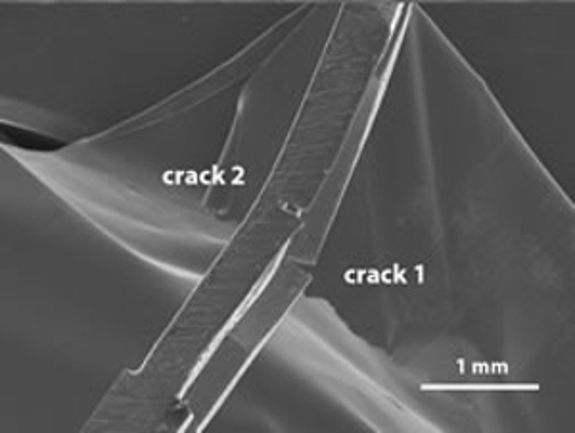 An image of the damaged High Tilt Retainer (HTR) focusing on two cracks magnified at 1 mm.